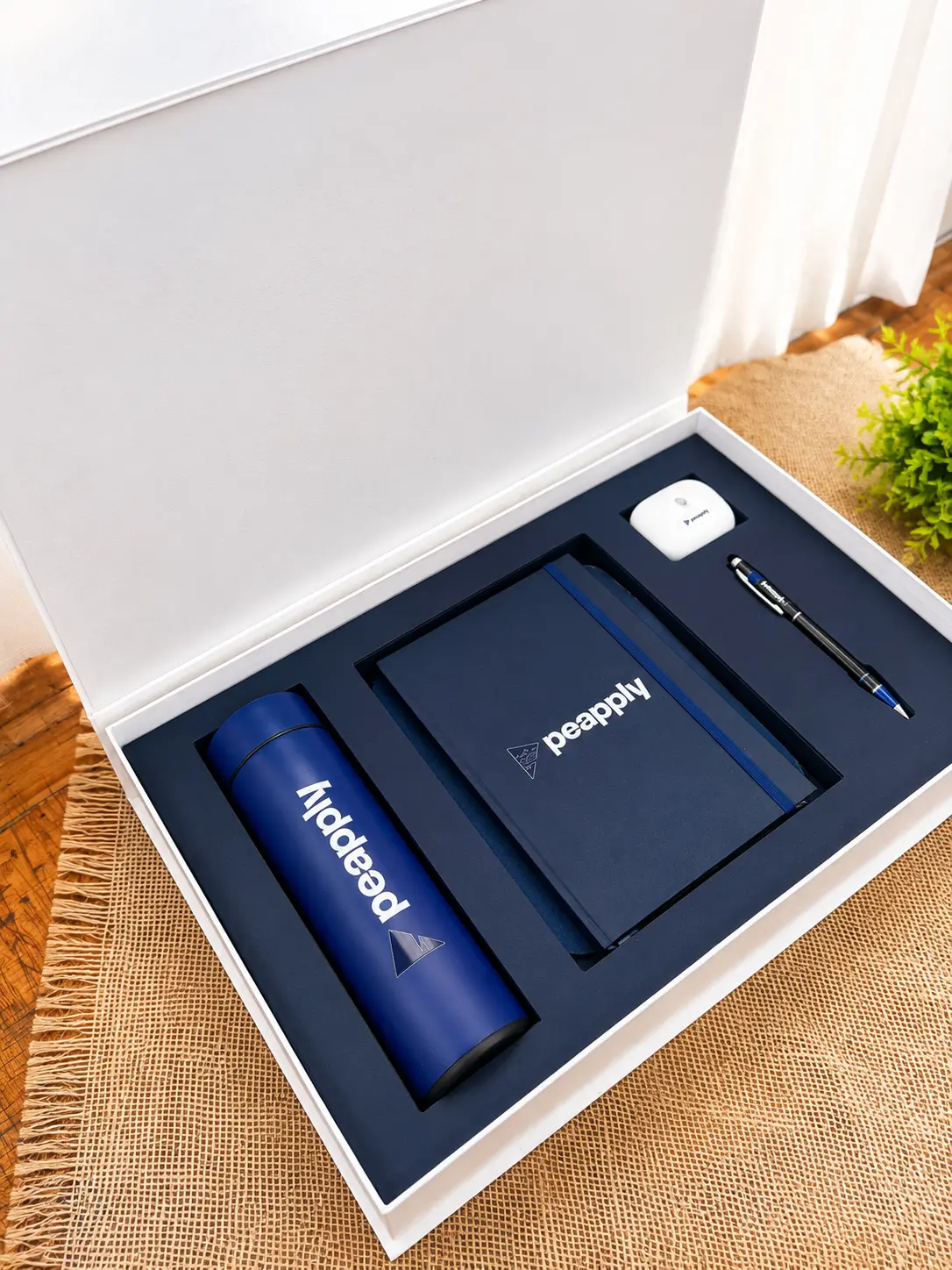 Kit de onboarding com caixa branca, berço azul, garrafa térmica, caderno e caneta com a logo da empresa